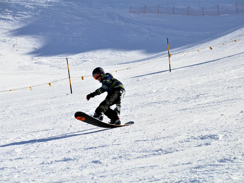 Snowboarder zwischen den Absperrstangen der Piste.